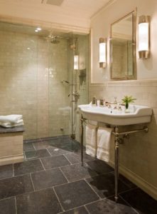 Luxurious bathroom with dark gray tile flooring, a seating area, and a walk-in shower.